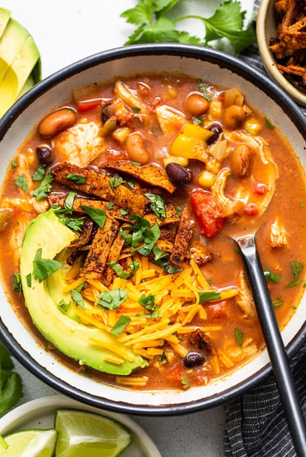 A Slow Cooker Chicken Tortilla Soup served with tortilla chips and guacamole.