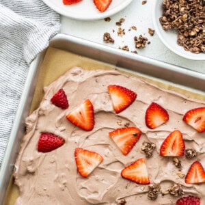 A sheet of chocolate cake with strawberries and graham cracker crumbs.