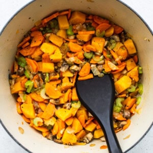 A pot filled with vegetables and turkey wild rice soup, alongside a black spatula.