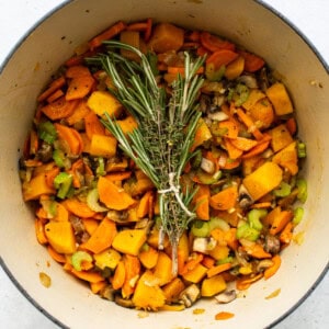 A pot filled with turkey, wild rice soup and sprigs of rosemary.