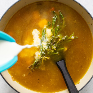 A bowl of turkey wild rice soup with milk being poured into it.