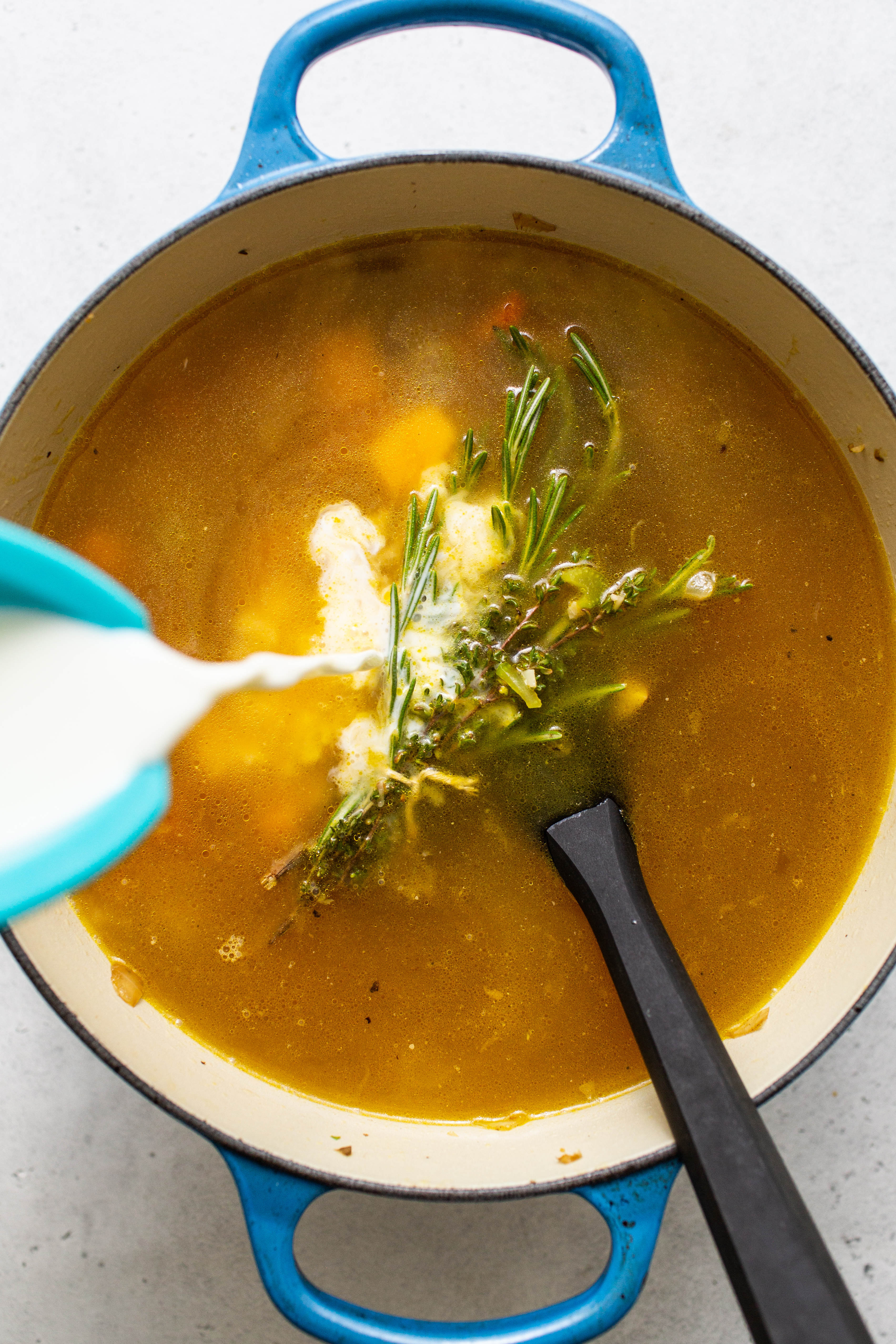 Milk being poured in a stock pot for turkey wild rice soup.