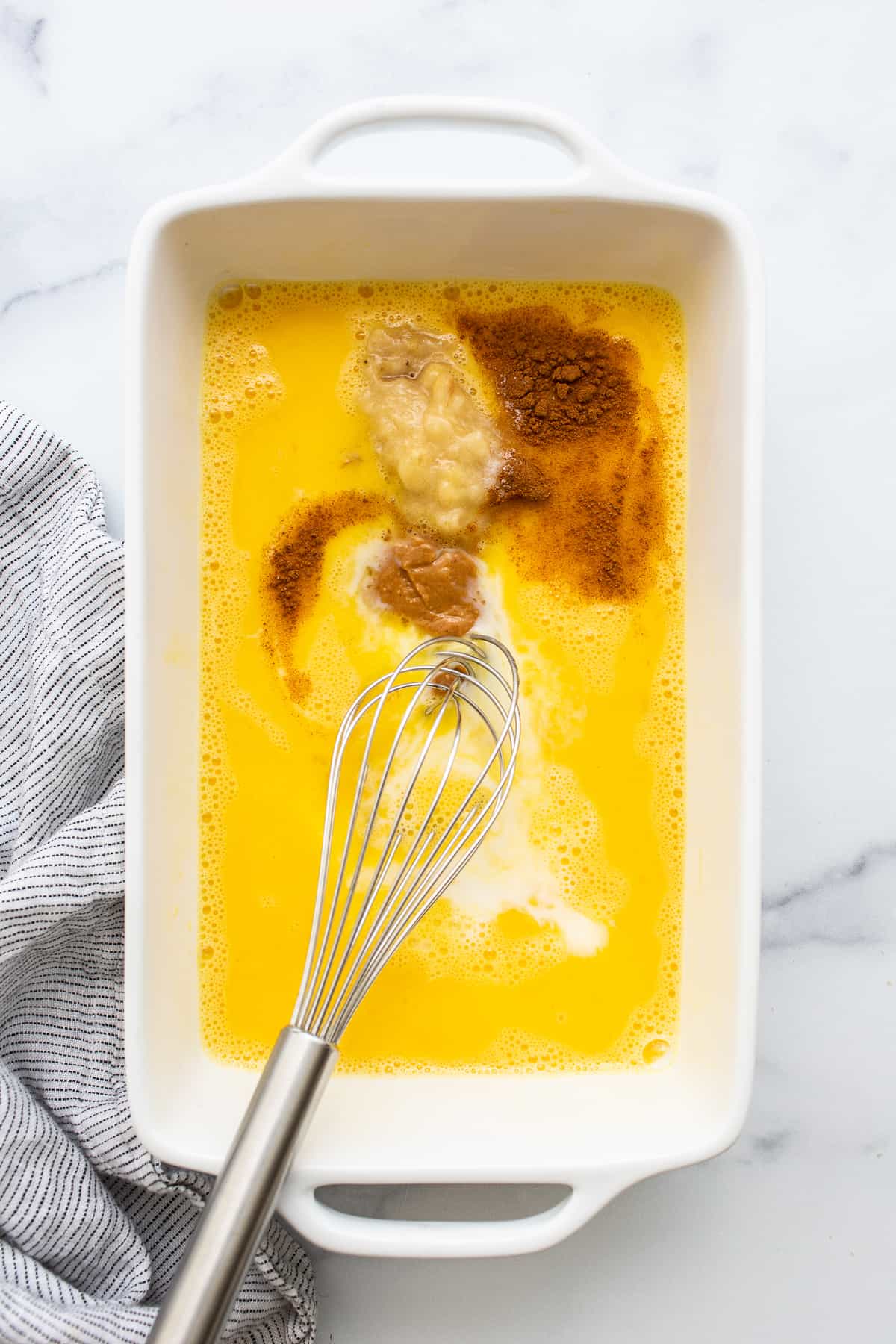 Egg wash for chunky monkey french toast in a bowl with a whisk.