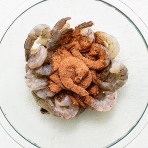 Shrimp in a glass bowl with spices on top.