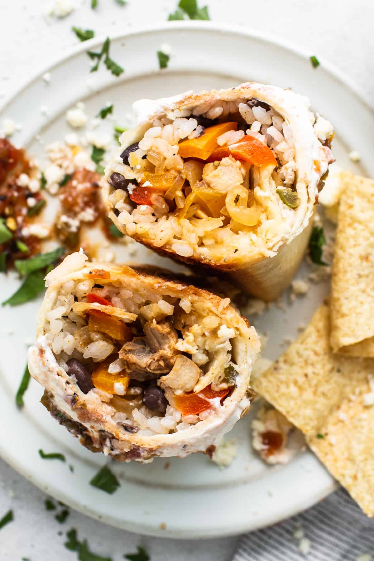 Chicken fajita burrito cut in half on a plate.