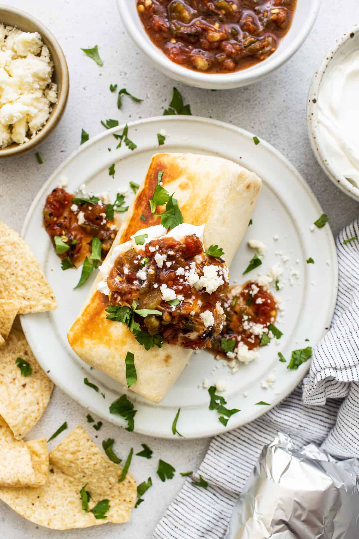 Chicken fajita burrito topped with salsa and sour cream.