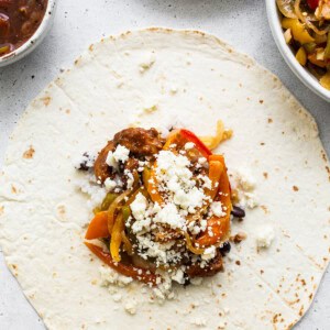 A mexican burrito with peppers and cheese on a plate.