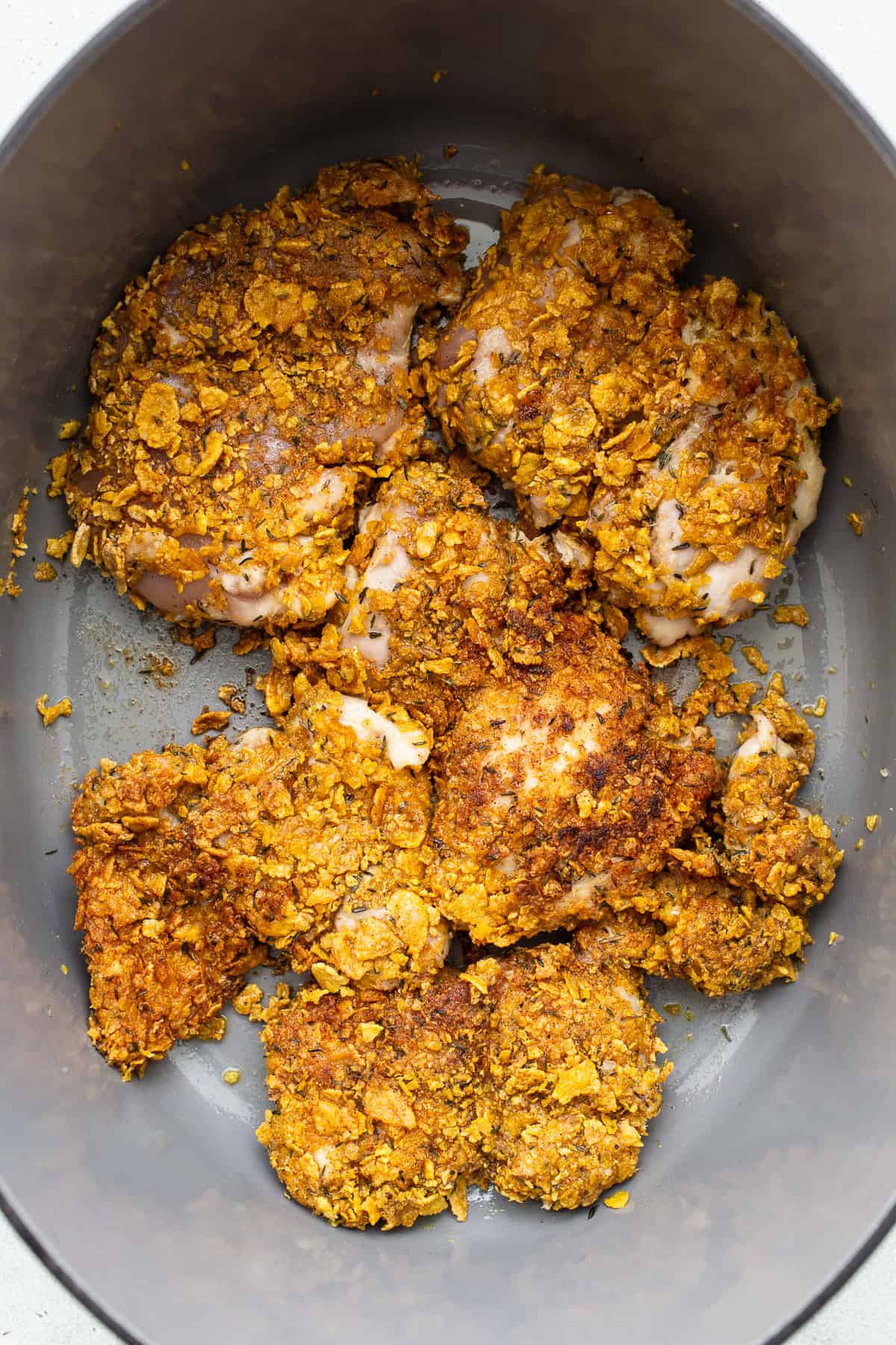 Breaded chicken being seared in a skillet.