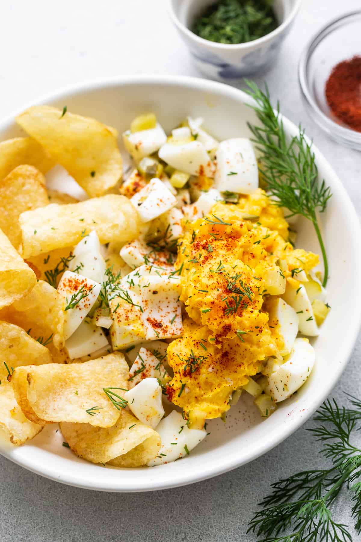 Deviled egg salad in a bowl with potato chips.