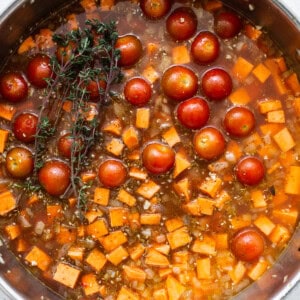 A pan filled with tomatoes and a sprig of thyme.