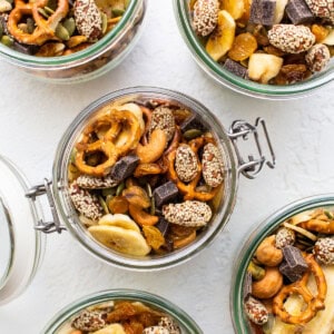 Four jars filled with nuts, seeds, and dried fruit.