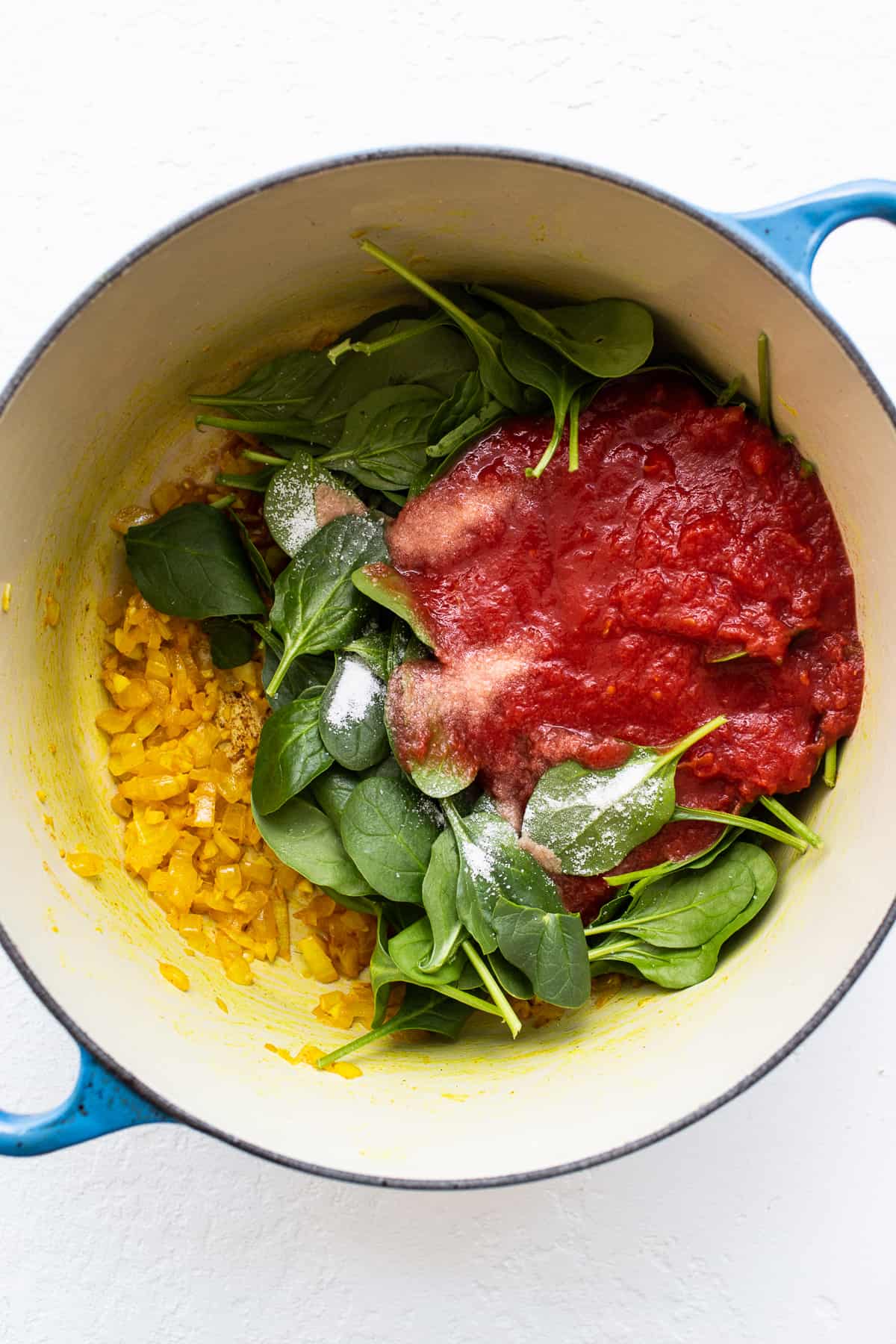 Spinach, crushed tomatoes and onions in a dutch oven.