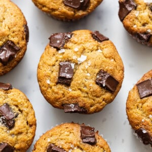 A group of chocolate chip muffins on a white surface.