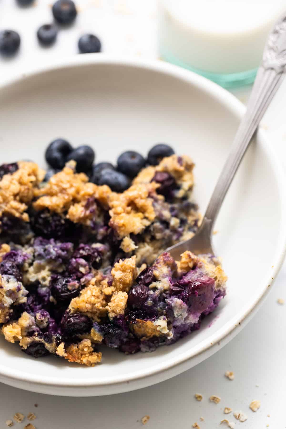 Blueberry muffin baked oatmeal in a bowl with a spoon.