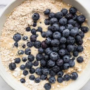 Blueberry pancake batter in a white bowl.