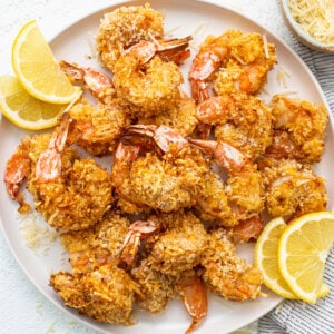 Air fryer shrimp on a plate with sliced lemons.