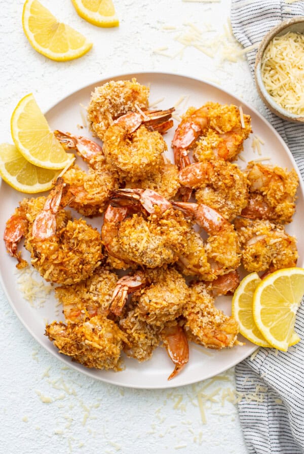 Air fryer shrimp on a plate with sliced lemons.