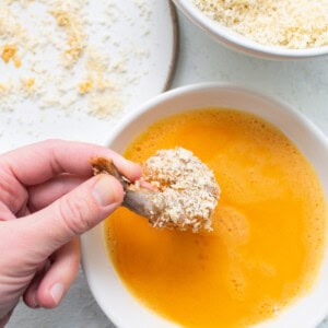 A person dipping a spoon into a bowl of soup.