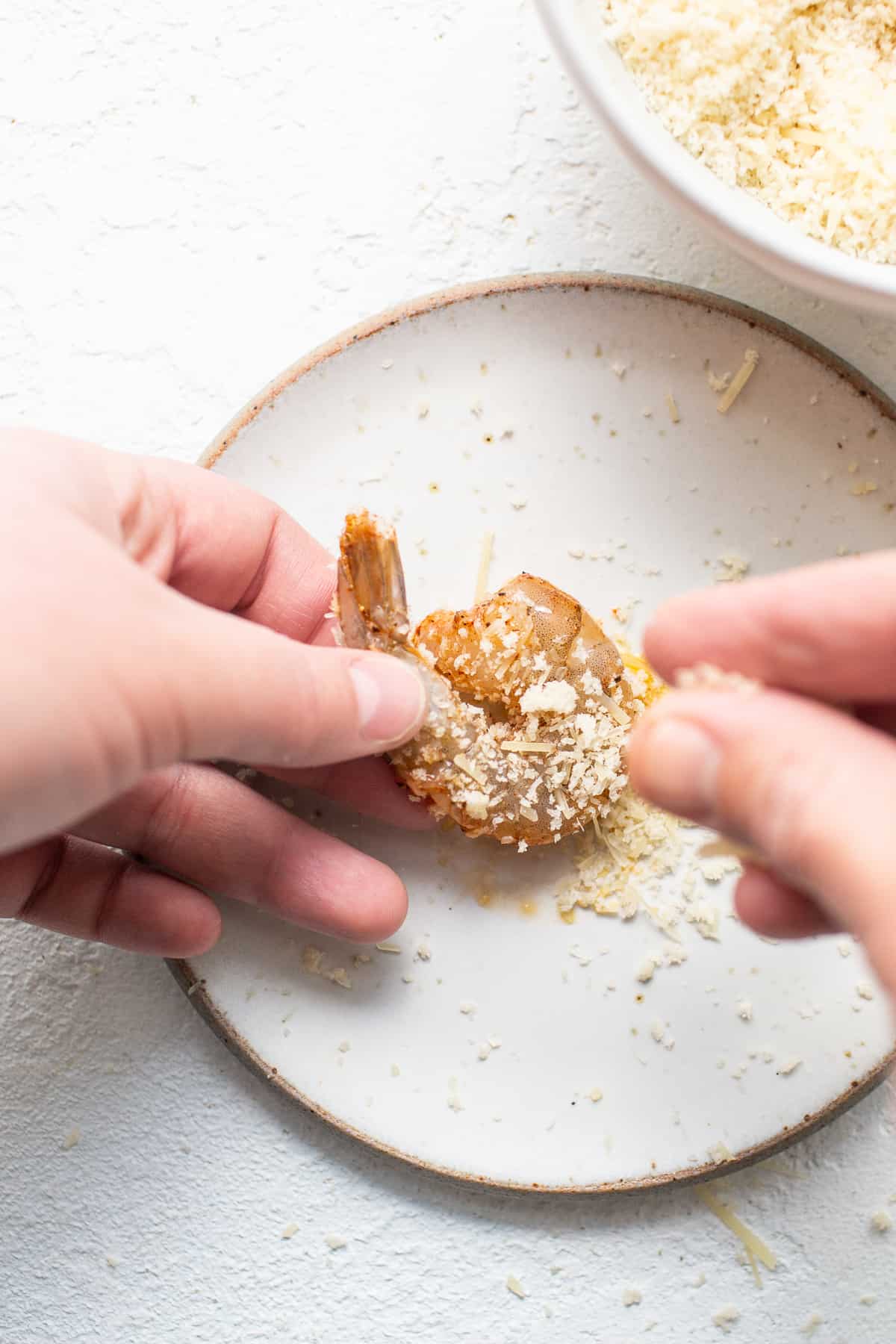 Shrimp being breaded with panko and parmesan.