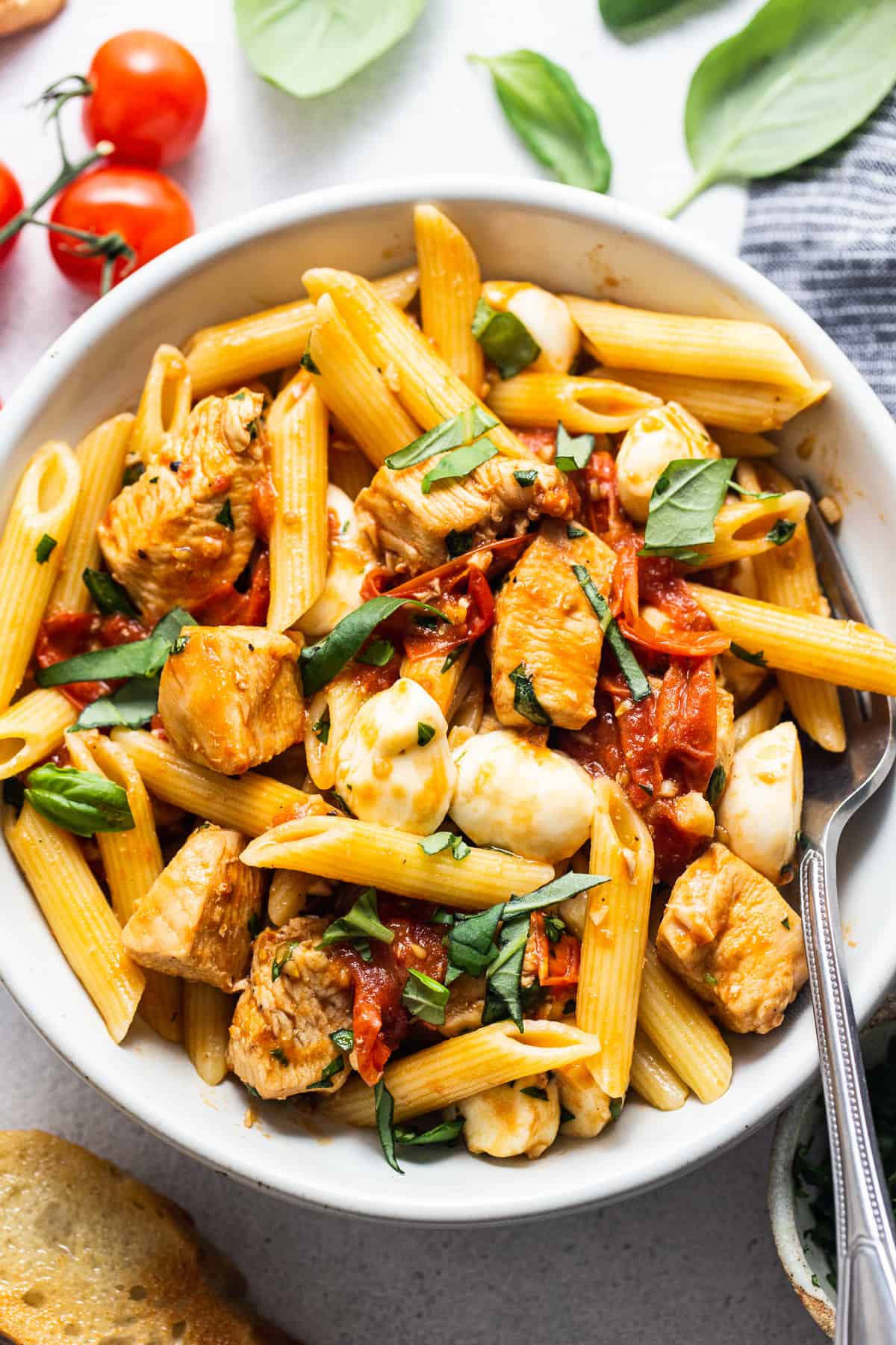 caprese chicken pasta in bowl with fork.