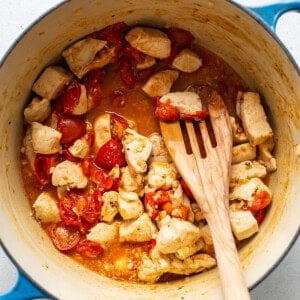 cooking chicken and tomatoes in large pot.