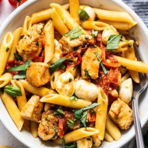 caprese chicken pasta in bowl with fork.