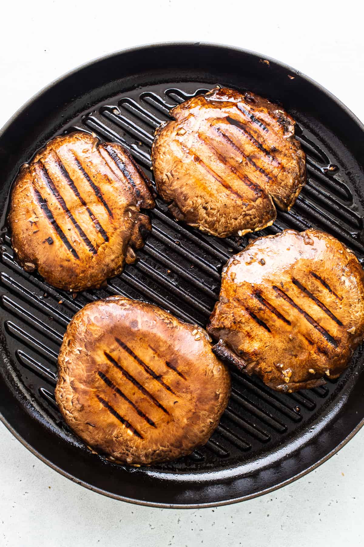 Portobello mushroom caps in a grill pan.