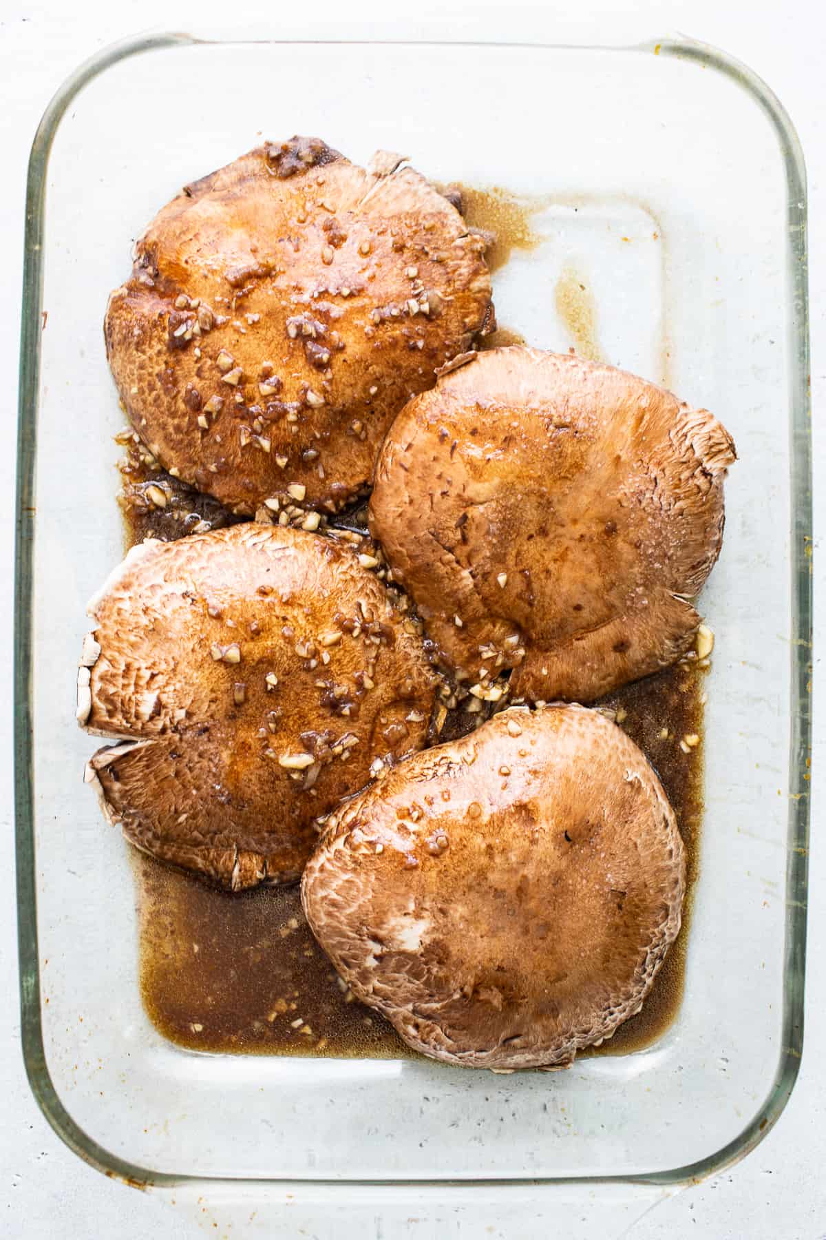 Portobello mushroom caps in a marinade.