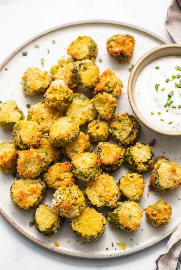 A plate of fried green beans with a dipping sauce.