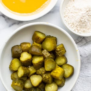 A bowl of pickles and a bowl of flour.