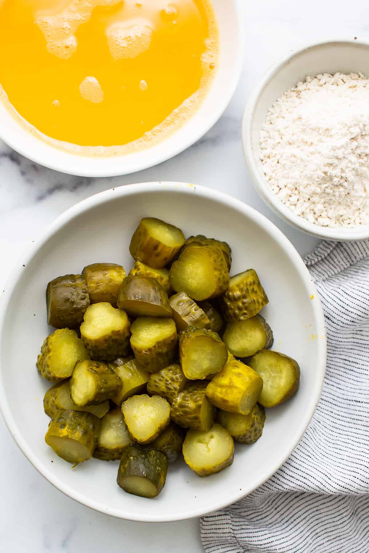 A bowl of pickles and a bowl of flour.