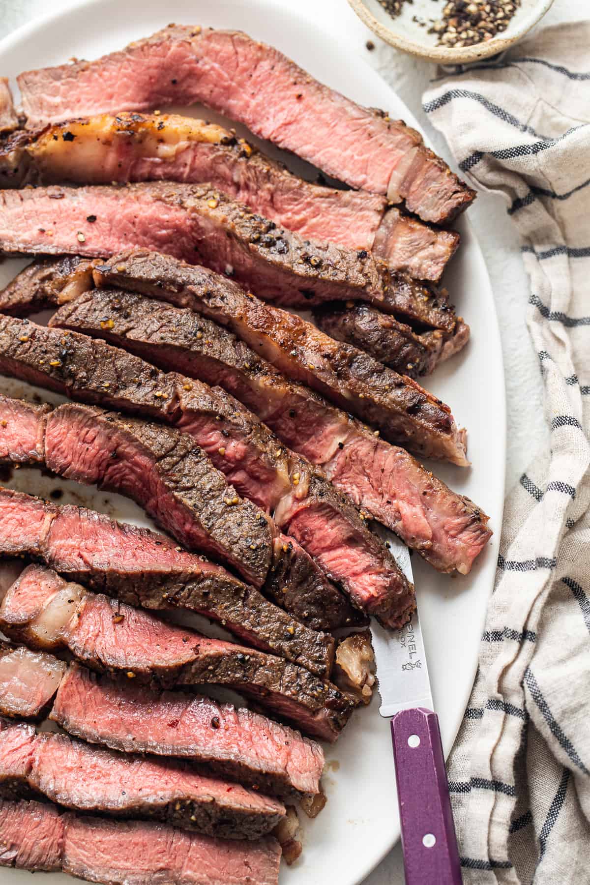 Sliced air fryer steak on a plate with a knife.