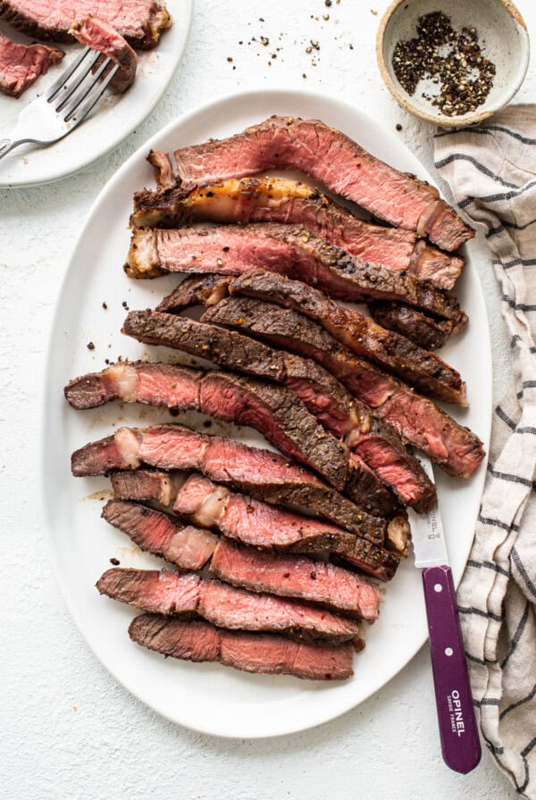 Sliced air fryer steak on a plate with a knife.