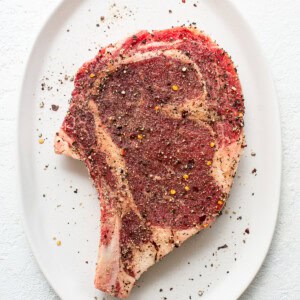 A piece of steak on a white plate.