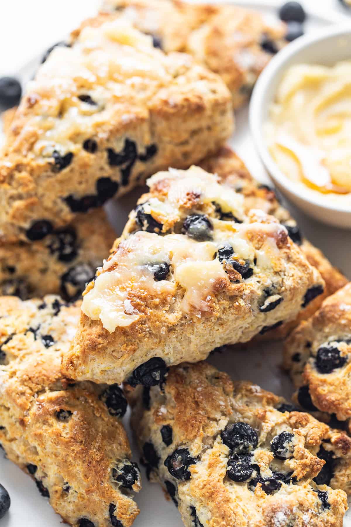 a white plate topped with blueberry scones next to a bowl of dip.