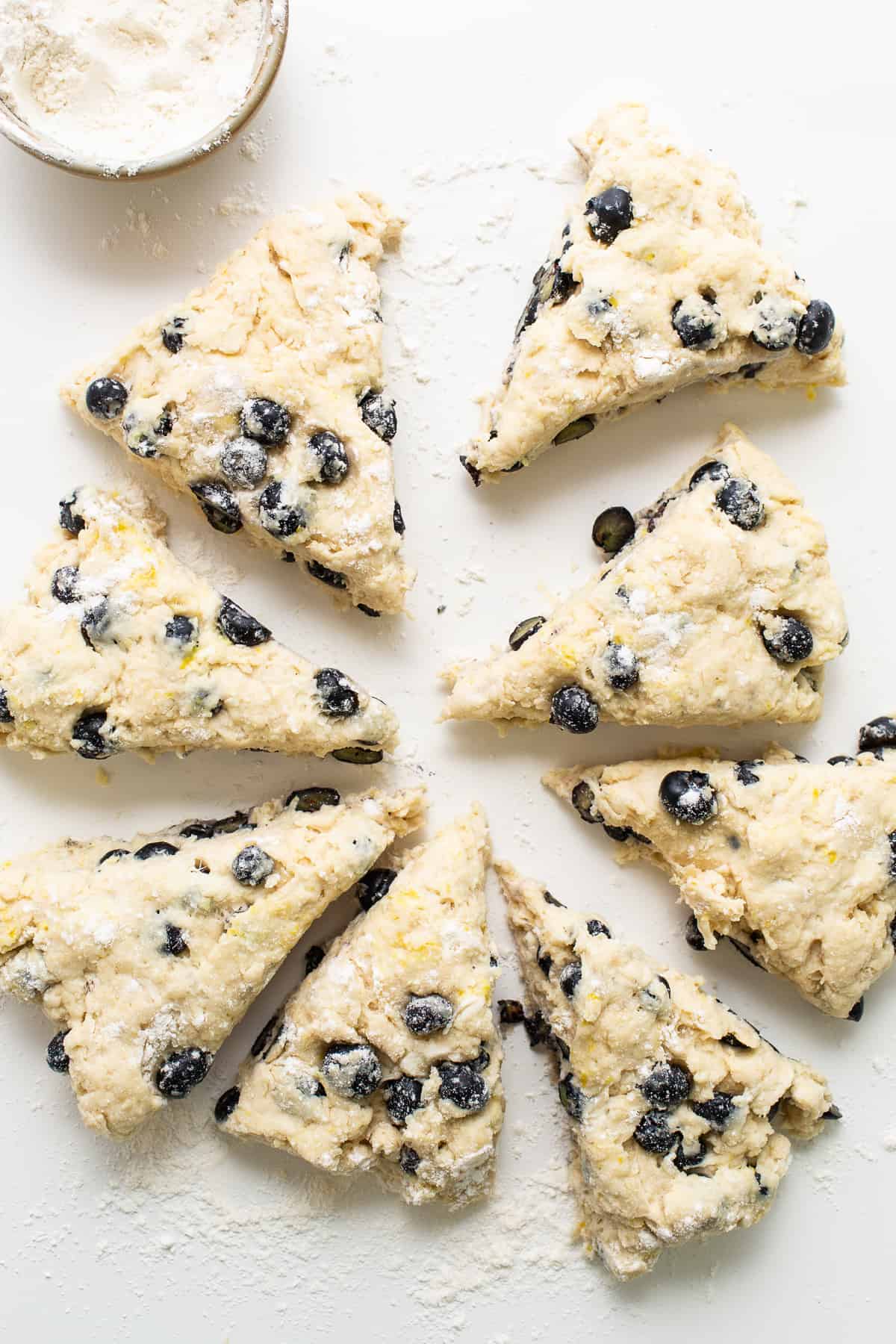 a white plate topped with blueberry scones next to a cup of milk.