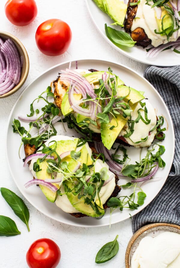 Two plates with avocado, tomatoes and onions on them.