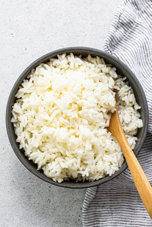 White rice in a bowl with a wooden spoon.