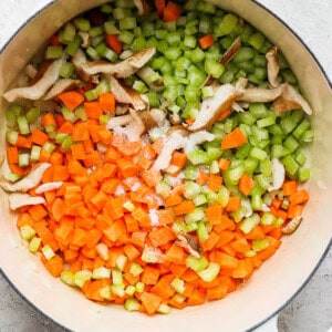 A pot with carrots, celery and mushrooms in it.