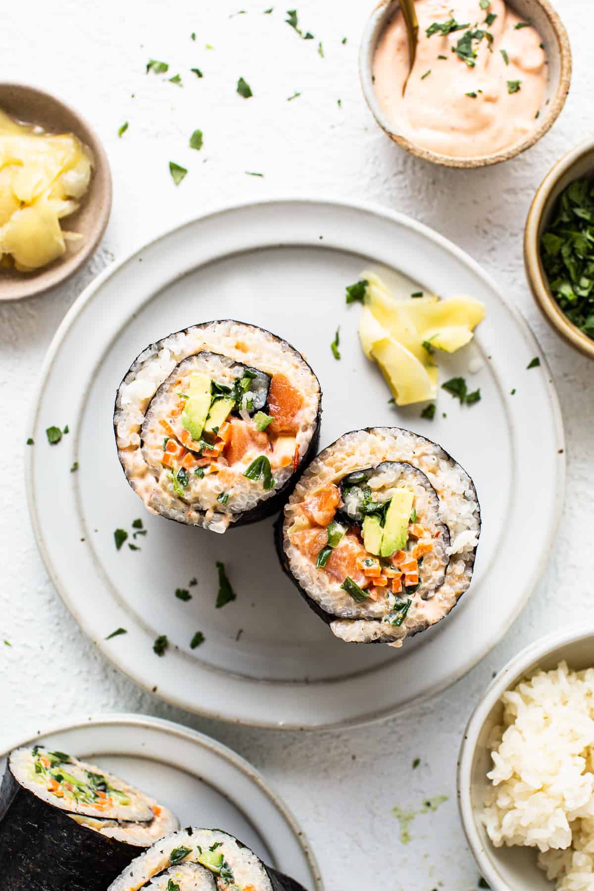 a white plate topped with sushi next to bowls of rice.