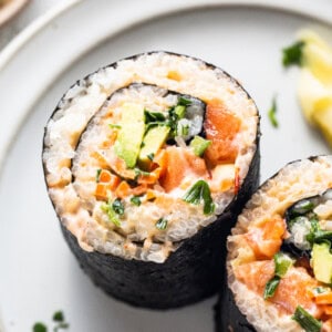 two sushi rolls on a plate with a lemon wedge.