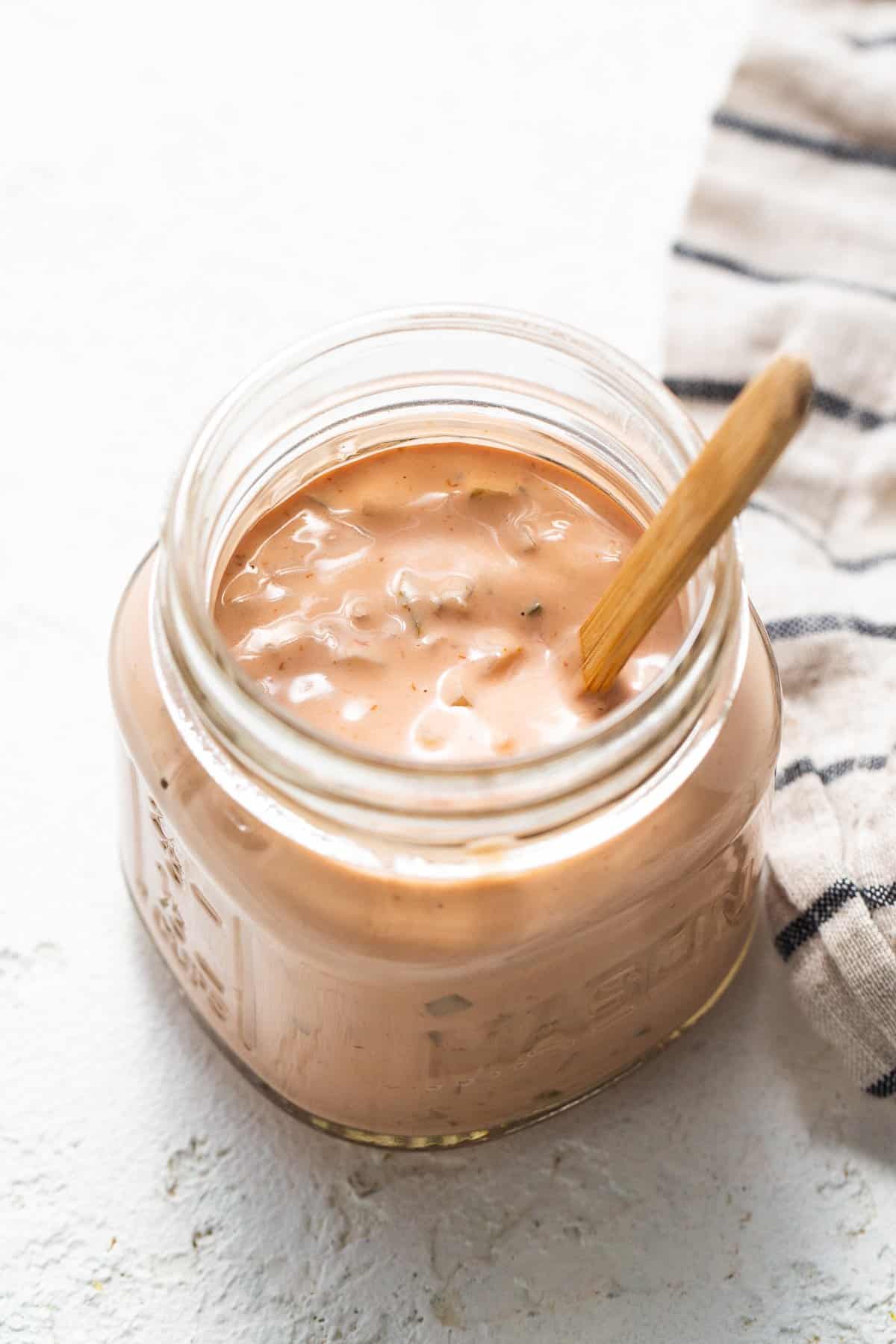 A jar of ketchup with a wooden spoon.