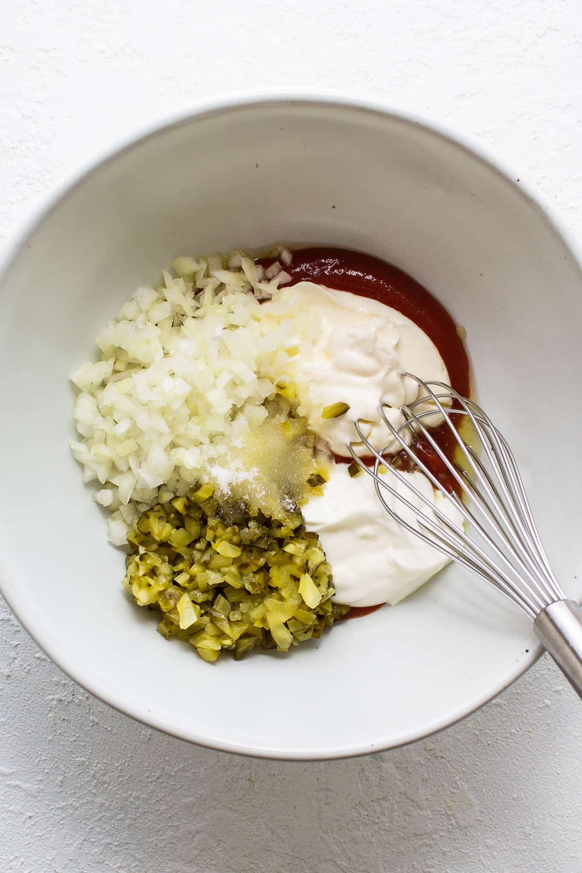 A bowl of ingredients with a whisk in it.