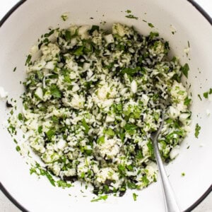 A white bowl filled with greens and a spoon.