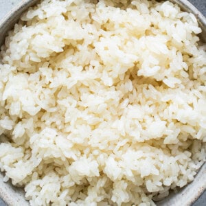 Rice in a bowl next to a bowl of water.