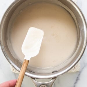 a person holding a spatula in a saucepan.