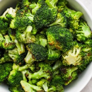 a white bowl filled with broccoli on top of a table.