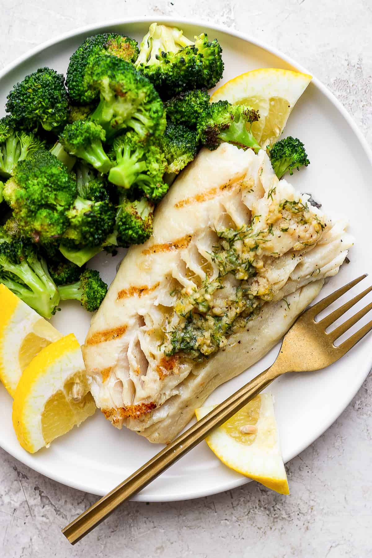 Grilled fish on a plate with broccoli.