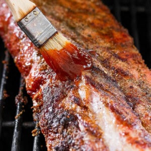 a bbq grill with a spatula of bbq sauce on it.