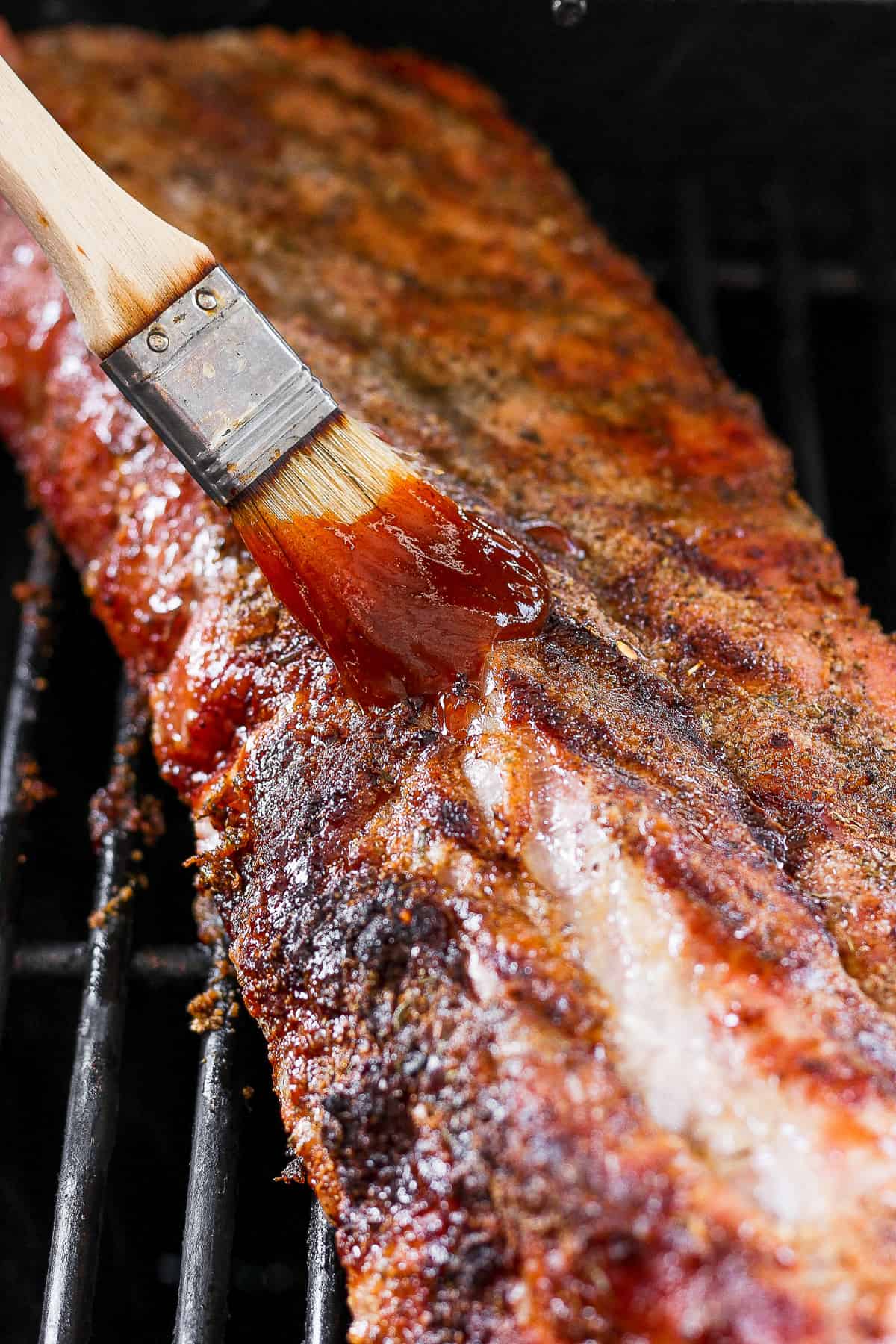 a bbq grill with a spatula of bbq sauce on it.